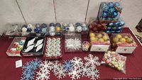 Wide shot showing multiple packages of Christmas balls and snowflake ornaments arranged on a surface.