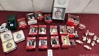 Overall view of the entire collection of Keepsake Hallmark collectible ornaments including boxed and unboxed items on a red surface.