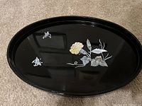 Top side of the black oval table piece showing flower and butterfly mother of pearl inlays.