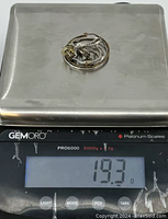 Group of twisted and braided sterling silver rings with gold tones on a scale showing 19.3 grams