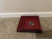All four square nesting wooden plates stacked together showing decreasing sizes and design.