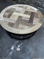 Top view showing round wooden tabletop with patterned slatted wood design in natural finishes.
