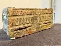 Lead block showing engraved text on one side with visible aging and wear