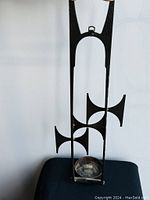 Front view of black cast iron Mid-Century Modern wall hanging candle holder showing full height and geometric shapes with candle tray.
