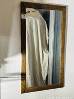 Full view of the rectangular oak framed mirror hanging on the wall.