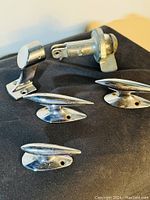 Three chromed stainless steel marine cleats, marine rail bracket, and a marine light fixture shown against a black background showcasing the retro style and chrome finish.