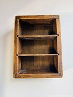 Front view of wooden display box showing three compartments with two removable partitions installed.