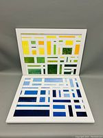 Two views of the acrylic abstract painting 'Lime & Cool Stelo' showing the full framed artwork with pattern of lime green, yellow, and blue rectangular shapes divided by white lines.