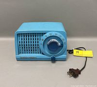 Front view of a blue Stewart Warner Model 9160 vintage radio showing the large tuning dial, smaller volume knob, front speaker grille, and the Stewart Warner metal logo.