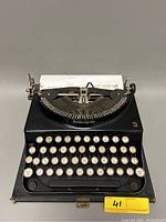 Front view of the Remington Model 3 typewriter with cream-colored keys and paper loaded in the platen.