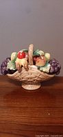 Front view of the ceramic fruit basket showing a woven basket and various colorful fruit.