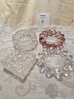 Front view of all four glass ashtrays/trinket dishes displayed on white textured fabric.