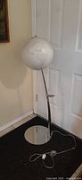 Photo showing the full lamp structure including the globe shade and round base.