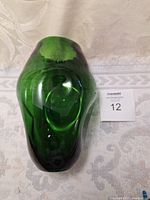 Top angled view of the green pinched glass vase showing the shape and color.