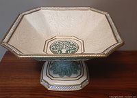 Top angled view of the octagonal ceramic centerpiece showing embossed leafy design, central green tree medallion, and footed pedestal base.