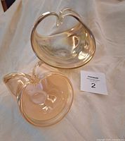 Both large and small glass baskets displayed together on a fabric background with a lot number tag.