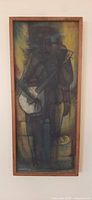 Full view of the framed painting showing an abstract figure holding a guitar with muted dark tones and subtle highlights. The figure occupies full height in a narrow rectangular frame.