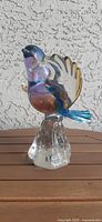 Full view of Murano style blown glass hummingbird figurine showing clear, purple, and blue hues and textured clear glass base