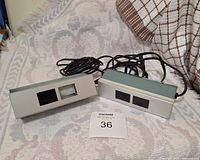 Pair of rectangular metal ultraviolet lamps lying on a patterned blanket with power cords visible.