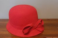 Front view of a red wool felt ladies hat with rounded crown and matching bow detail