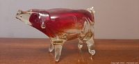 Side view of MCM handblown uranium glass pig figurine showing amber to red color gradient and clear glass legs, ears and snout.