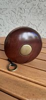 Side view of vintage Bombay Company wooden yo-yo showing polished brown wood and brass center.