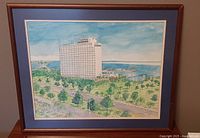 Framed watercolor showing the hotel and surrounding greenery and water.