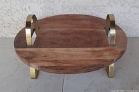 Angled side view showing the thickness of the wooden tray, brass handles, and the brass feet lifting the tray off the surface.