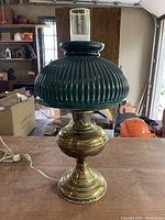 Full view of antique oil lamp with green ribbed glass shade on brass base