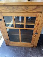 Front angle shot of antique pine bookcase door showing glass panes and wood grain.