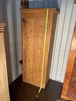 Full view of antique pine single door chimney cupboard with measuring tape showing height.