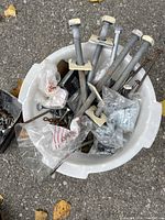 Close-up angle of the bucket showing large galvanized bolts with washers along with assorted small bolts and hardware pieces inside the bucket.