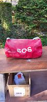 Red SOS emergency bag on table outdoors with some wear visible