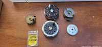 Top-down view of 4 fly fishing reels and 2 line spools on wood table