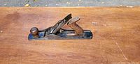 Top angled view of the metal hand plane showing the wooden front knob and repaired handle