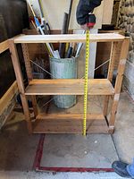 Front view of 3 shelf wooden unit with measuring tape showing height around 37.5 inches.