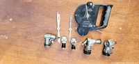 Five vintage model airplane engines and a black U control handle on wooden surface