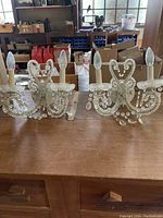 Pair of glass and crystal wall sconces with candle-style bulbs on a wooden table indoors