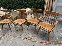Four oak spindle-back chairs arranged outdoors showing two armchairs and two armless side chairs
