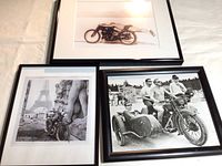 Three framed black and white photographs featuring motorcycles and men, arranged together on a surface.