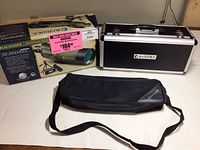Barska Blackhawk spotting scope box, hard aluminum carrying case, and soft carrying case with shoulder strap on a white surface.