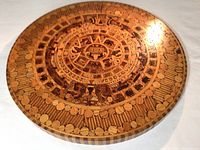 Top-down photo of wooden Aztec calendar showing circular intricate carvings.