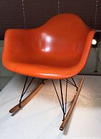 Front-angle view showing orange fiberglass shell and black wire base on wood rockers