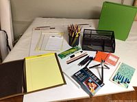 Overview of office supplies including pens, pencils, paper, notebooks, and organizers on a white surface