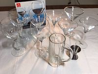Set of 4 wine glasses, 4 martini glasses, a glass beer mug, and a metal jigger arranged on a table with packaging boxes visible for wine glasses.