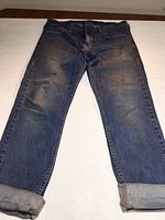 Front view of vintage blue denim Levi's 511 jeans with visible fading, worn look, and cuffed legs.