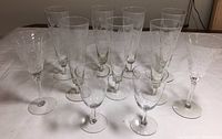 7 etched stemware glasses with leaf pattern: 5 pilsners and 2 smaller wine glasses, shown from front.