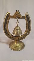 Front view showing the bell hanging in the center of the upturned horseshoe with the horse's head mounted at the top and "Good Luck" inscription at the base.