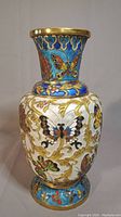 Full front view of cloisonné metal vase showing butterfly and vine pattern with gold accents.