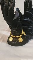 Bracelet displayed on black velvet hand stand showing overall gold tone and medallions.